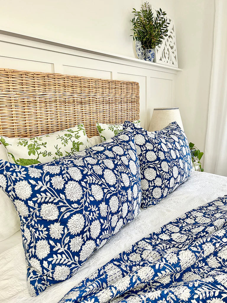 Bed with blue and white floral bedding and pillows in a bedroom setting.