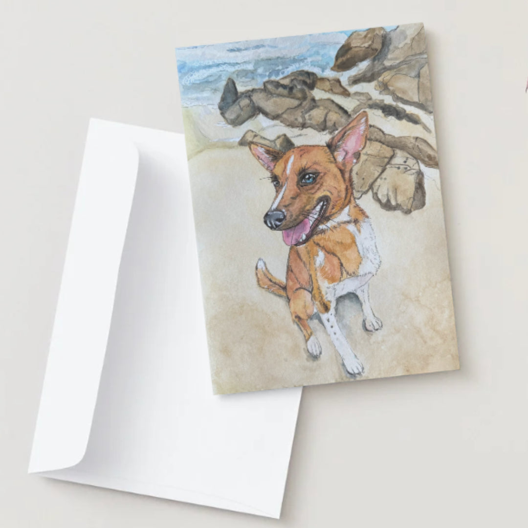 Card with a dog illustration on a beach scene, featuring a white envelope.