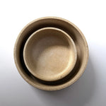 Three nested ceramic bowls in a light beige stoneware finish, photographed from directly above on a white background.