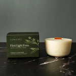 Lunaire candle and packaging on a dark surface with a gray background