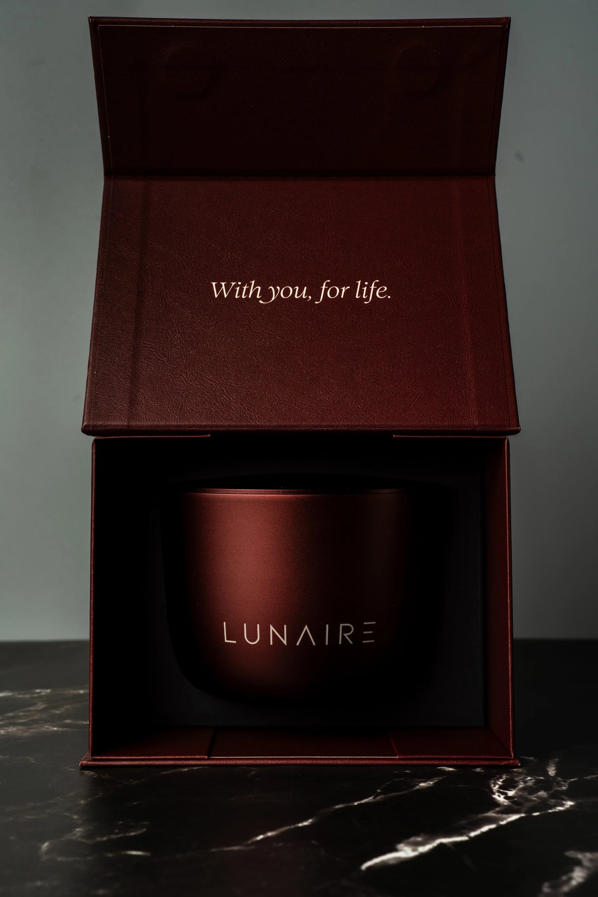 Red mug with 'LUNAIRE' branding in an open box on a dark surface.