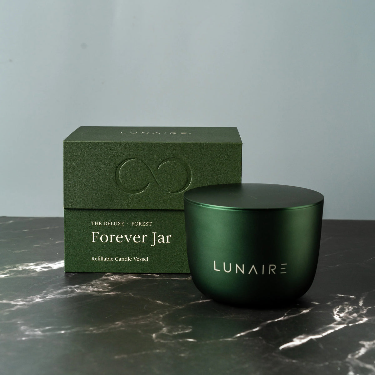 Green candle jar and box with 'LUNAIRE' branding on a marble surface.