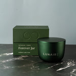 Green candle jar and box with 'LUNAIRE' branding on a marble surface.