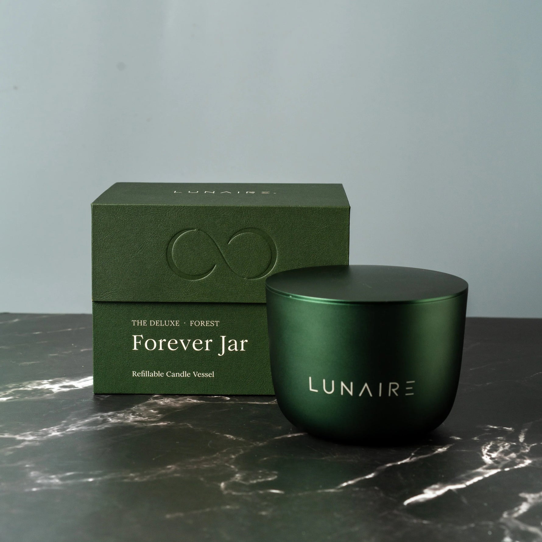 Green candle jar and box with 'LUNAIRE' branding on a marble surface.