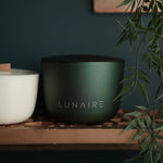 Green pot with 'LUNAIRE' branding on a wooden surface with a plant in the background