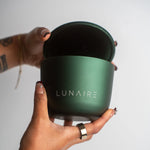 Green container with 'LUNAIRE' branding held by a hand against a light background