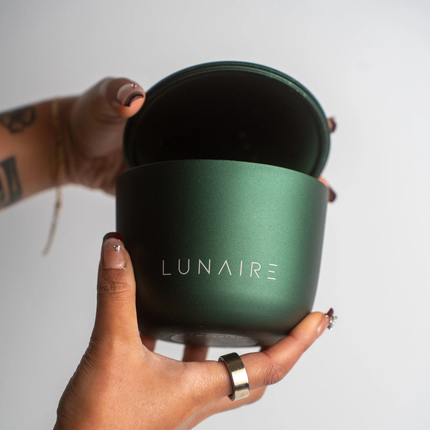 Green container with 'LUNAIRE' branding held by a hand against a light background