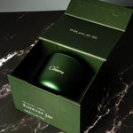 Green candle jar with 'Chiuwa' branding inside an open green box on a dark marble surface.