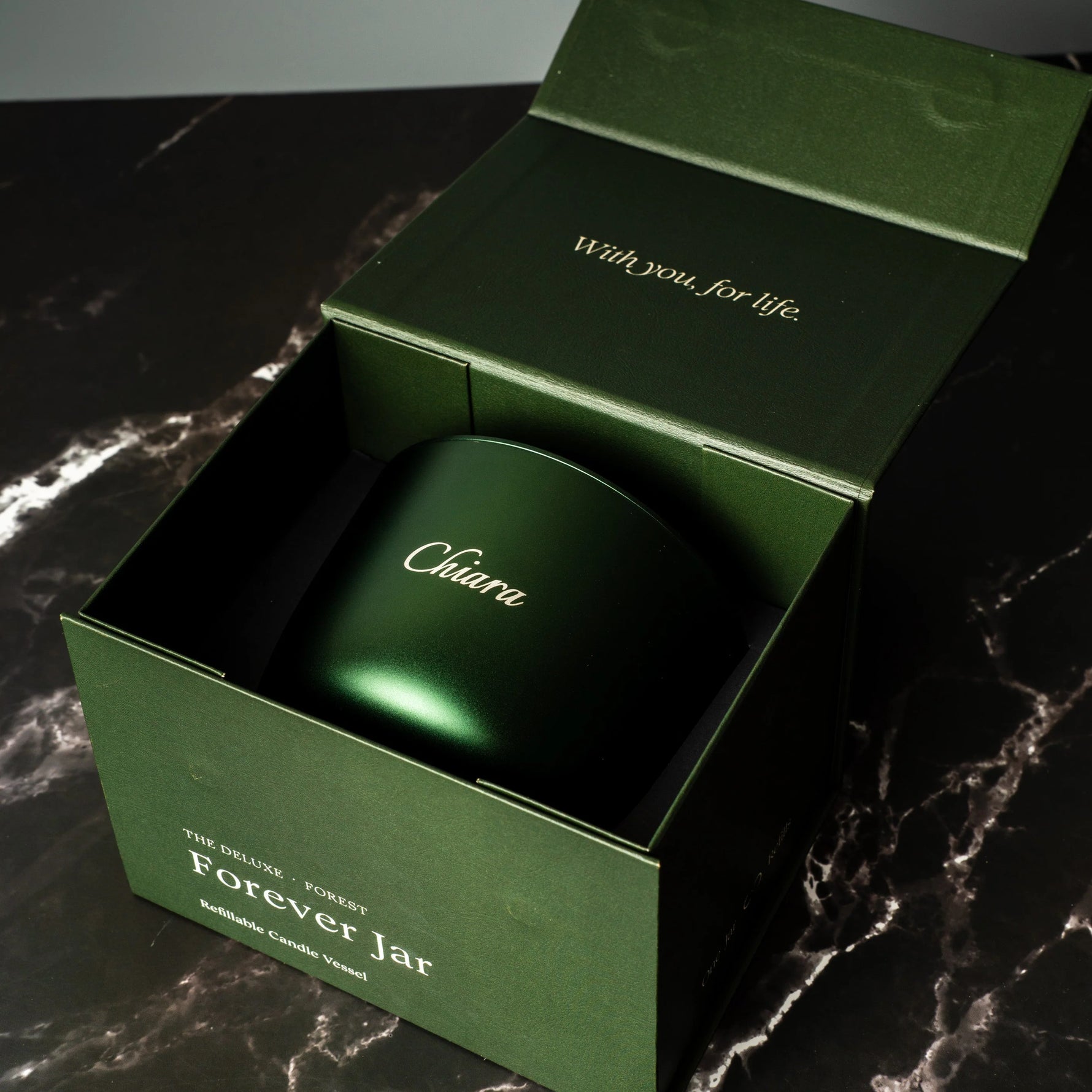 Green candle jar with 'Chiuwa' branding inside an open green box on a dark marble surface.