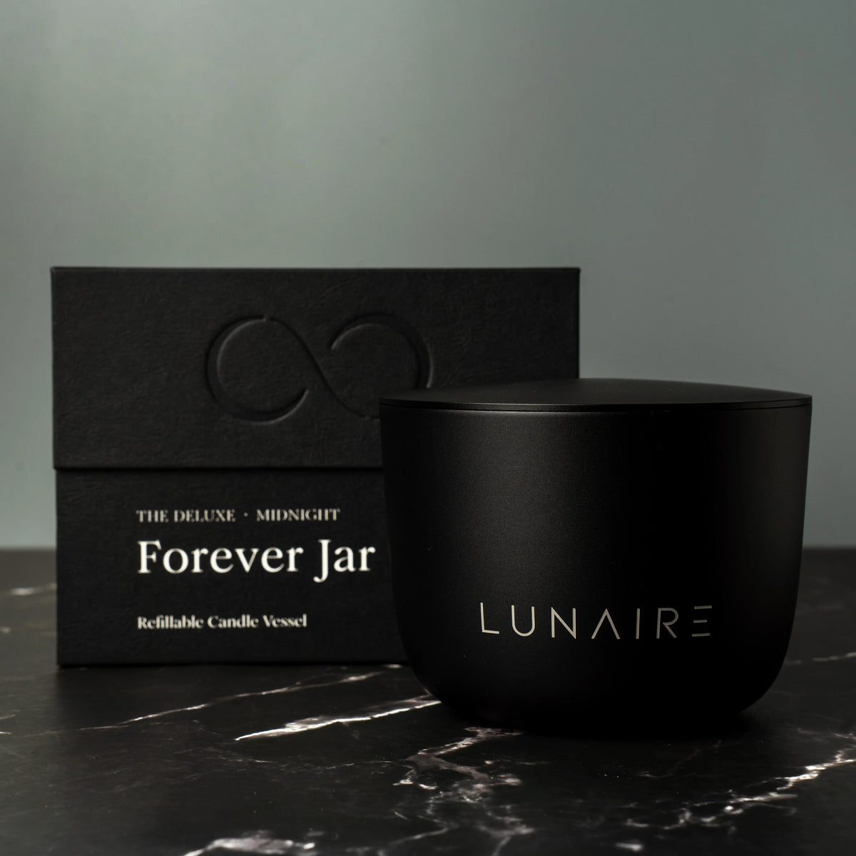 Black candle jar with 'LUNAIRE' branding next to its packaging on a dark surface.