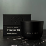 Black candle jar with 'LUNAIRE' branding next to its packaging on a dark surface.
