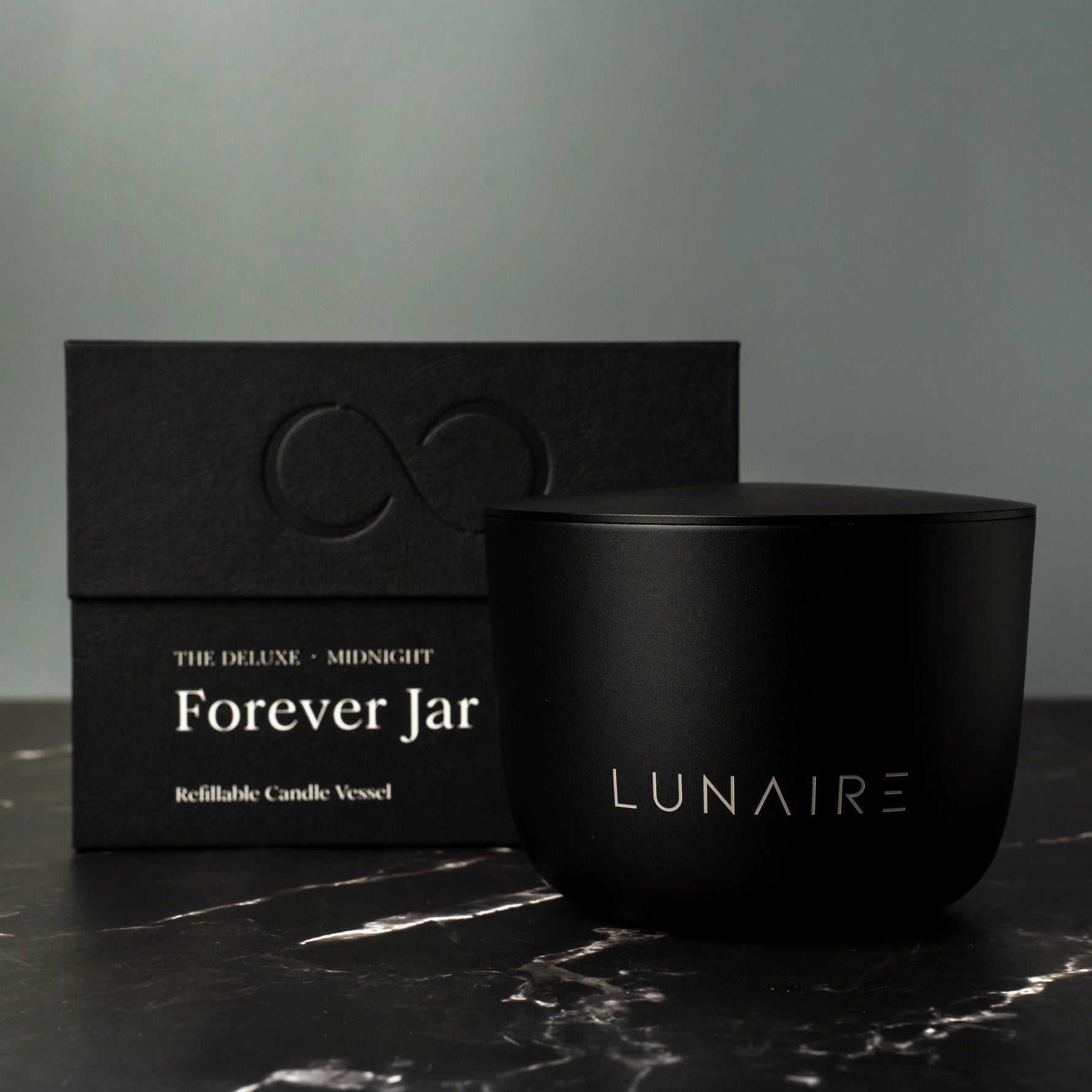 Black candle jar with 'LUNAIRE' branding next to its packaging on a dark surface.