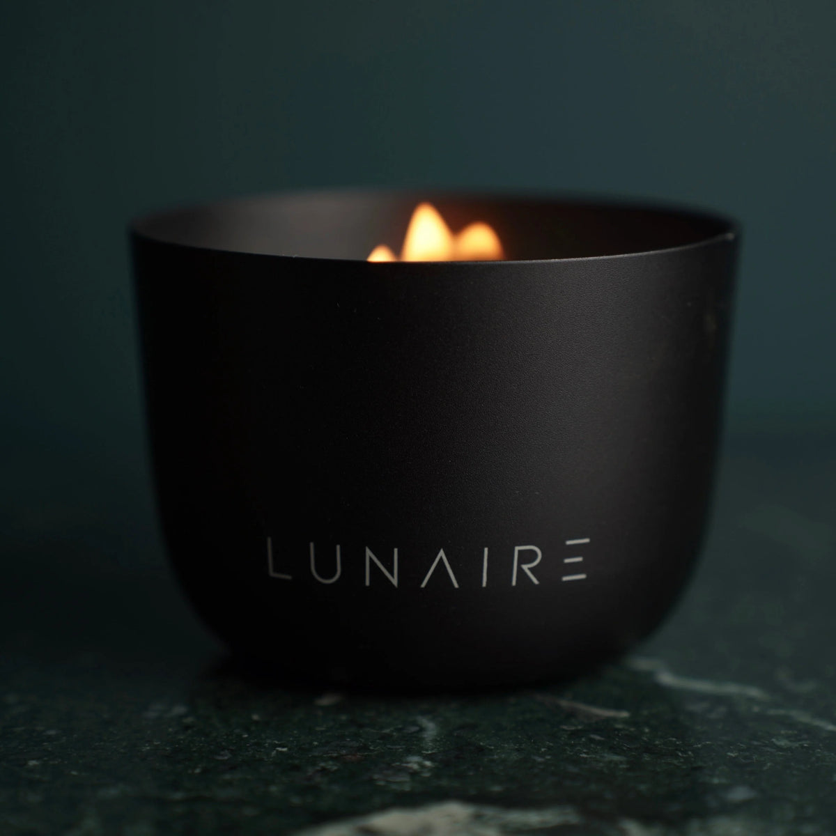 Black 'LUNAIRE' bowl with a small flame on a dark background