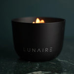 Black 'LUNAIRE' bowl with a small flame on a dark background