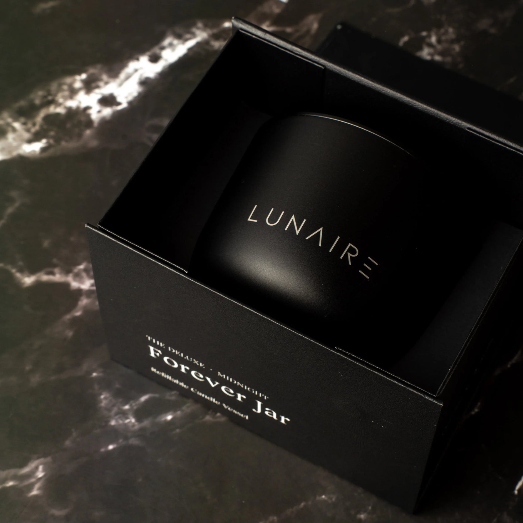 Black 'LUNAIRE' container in a box on a dark marble surface