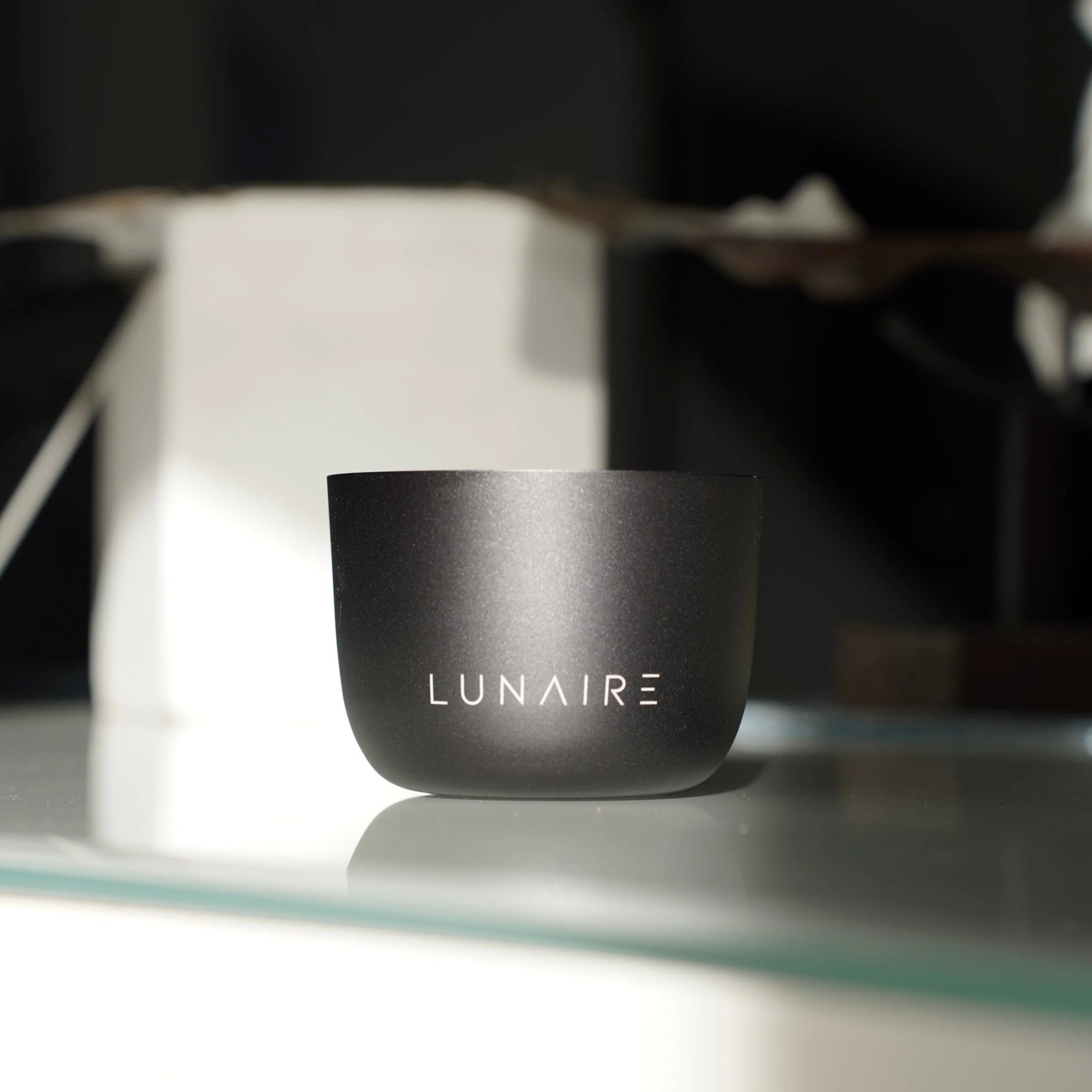 Black container with 'LUNAIRE' branding on a reflective surface