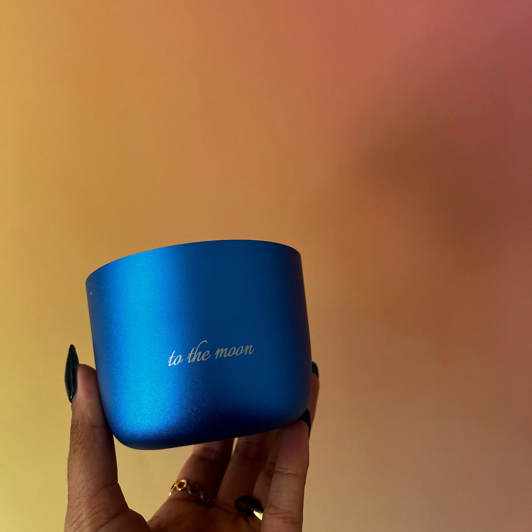 Blue container with 'to the moon' text held by a hand against a blurred background