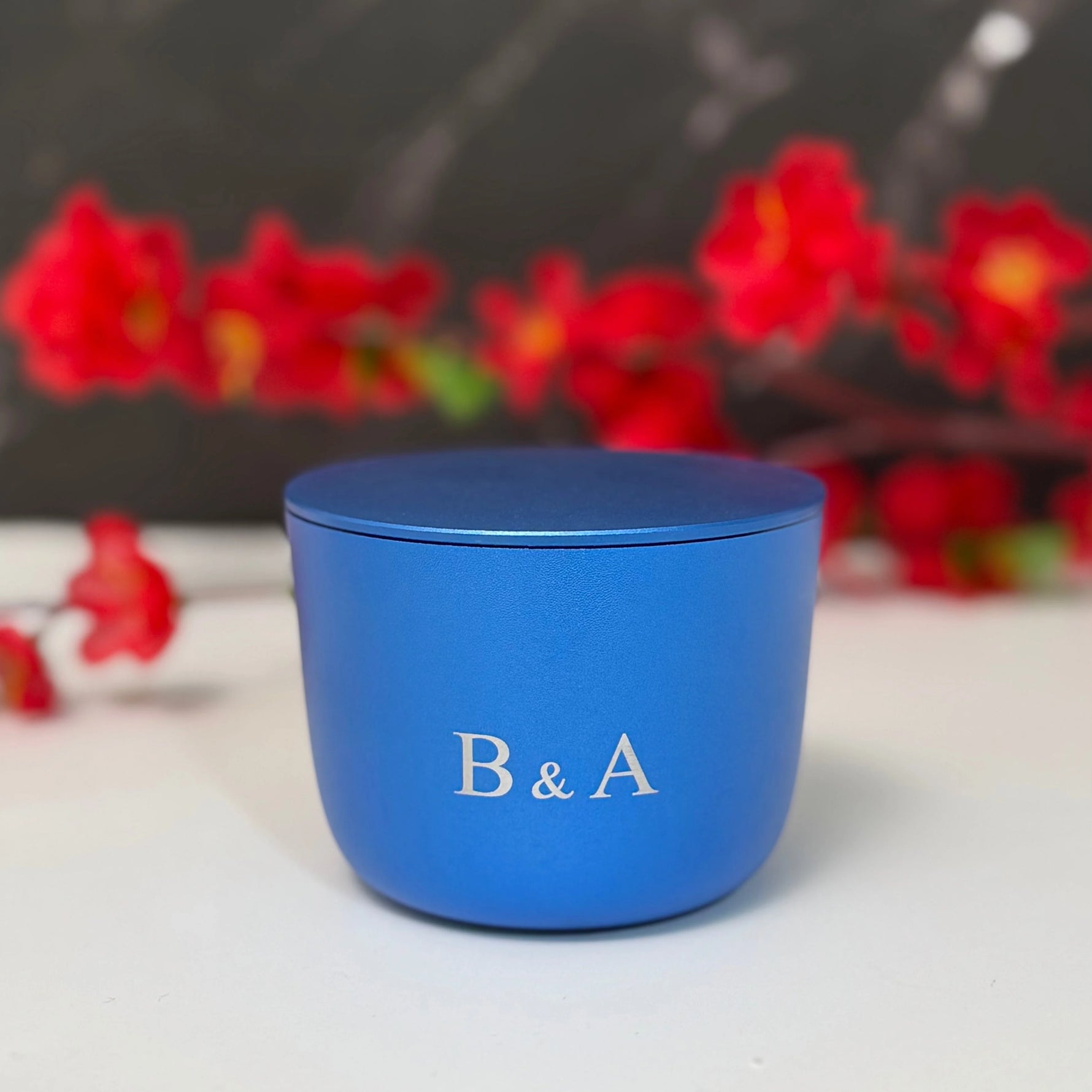Blue container with 'B & A' branding in front of red flowers