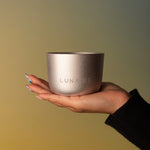 Hand holding a metallic cup with 'LUNA RE' branding against a gradient background