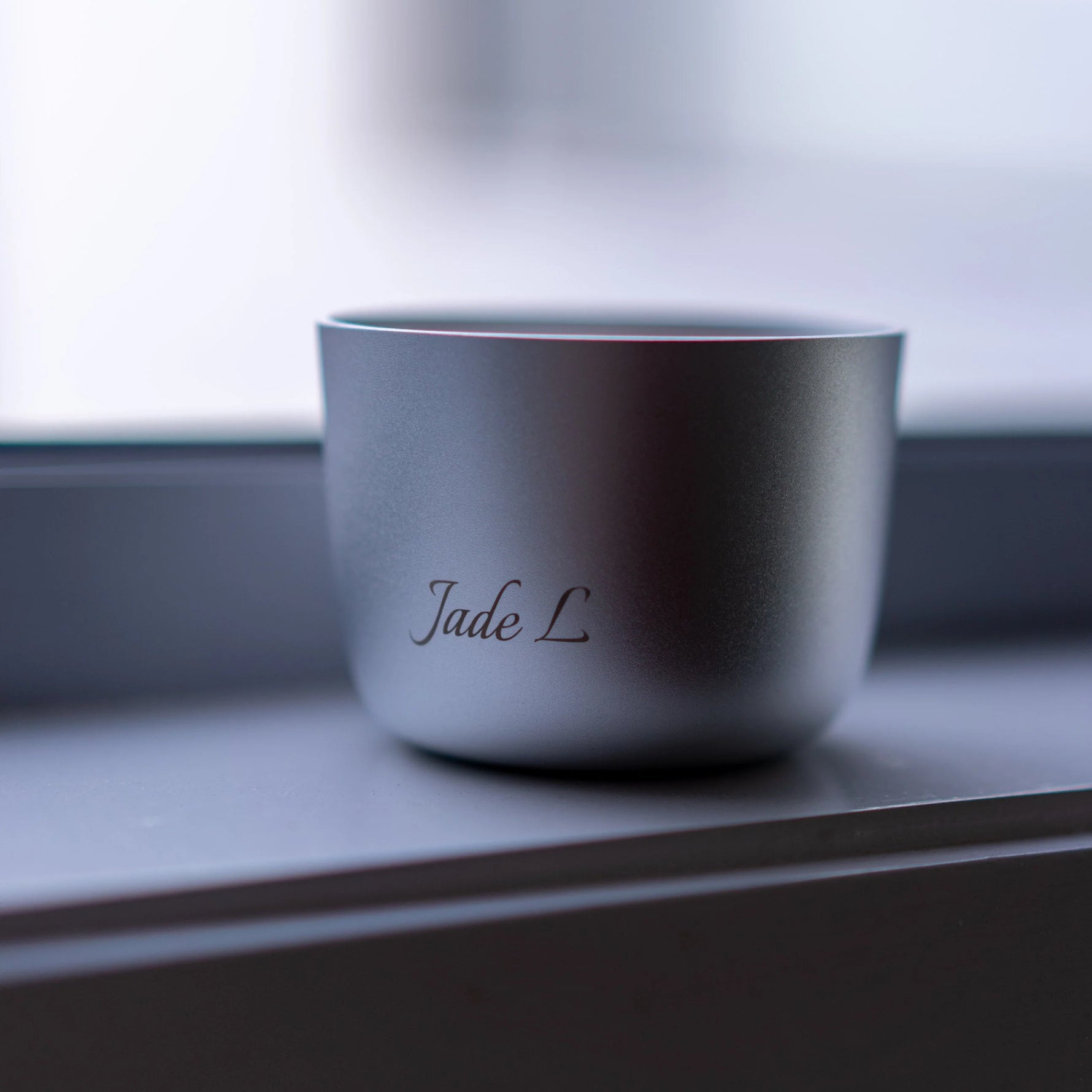 Silver cup with 'Jade L' engraving on a reflective surface