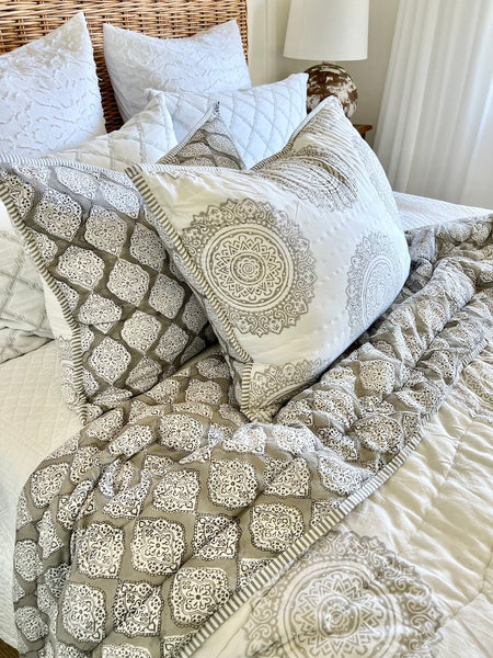 Patterned quilt and pillows on a bed in a bedroom setting