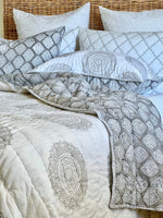 Patterned bedding set with a quilt and pillows on a bed.