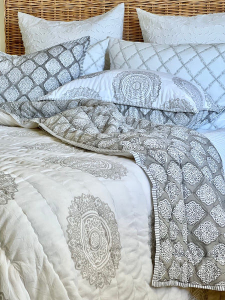 Patterned bedding set with a quilt and pillows on a bed.