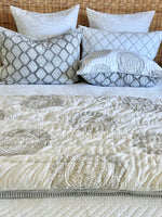 Patterned quilt and pillows on a bed with a wicker headboard