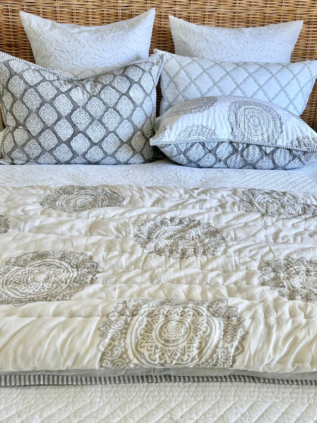 Patterned quilt and pillows on a bed with a wicker headboard