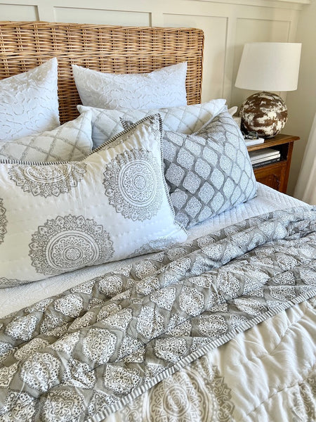 Bed with patterned bedding and pillows in a bedroom setting