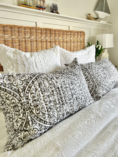 Bed with patterned bedding and wicker headboard in a bedroom setting.