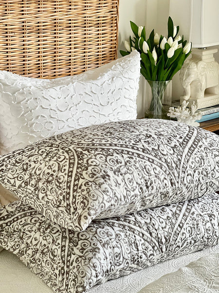 Patterned bedding with white pillows on a bed in a bedroom setting.