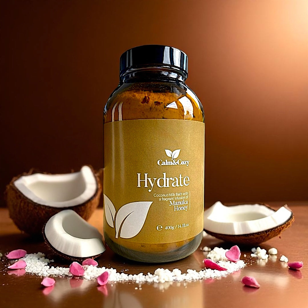 Bottle of 'Hydrate' with coconuts and pink petals on a brown background