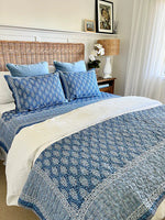 Bed with blue and white patterned bedding in a bedroom setting.