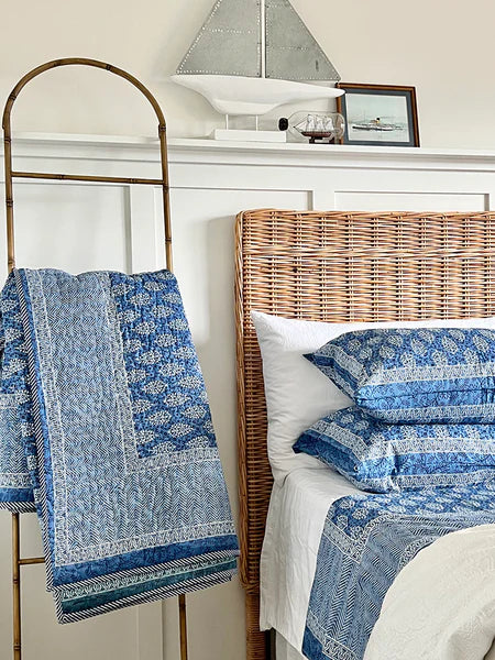 Bed with wicker headboard and blue patterned bedding