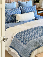 Bed with blue and white patterned bedding and pillows.