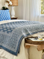 Bed with blue and white patterned quilt in a bedroom setting