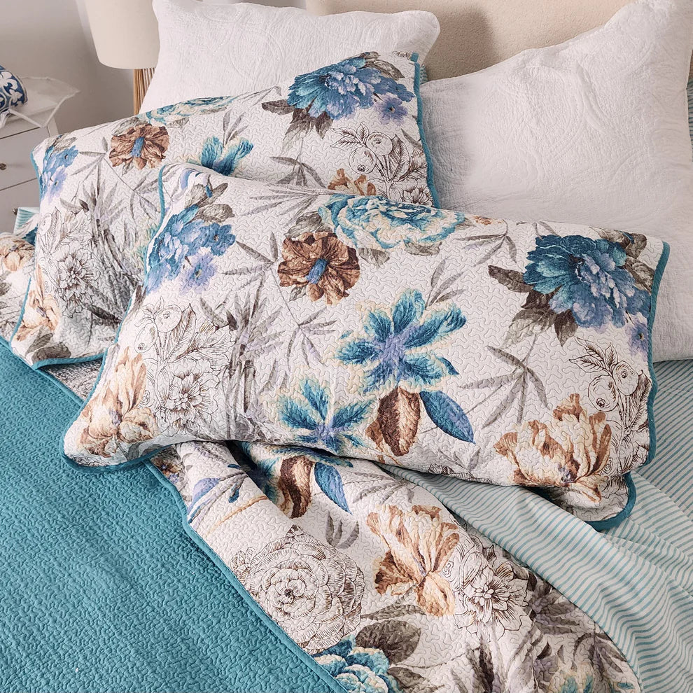 Floral patterned pillows on a bed with teal bedding