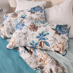 Floral patterned pillows on a bed with teal bedding
