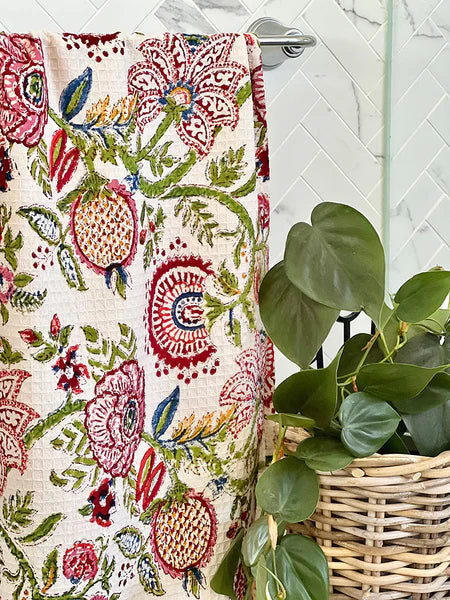 Floral-patterned towel hanging on a rack with a plant in the background