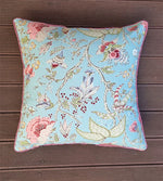 Decorative pillow with floral and butterfly pattern on a wooden surface