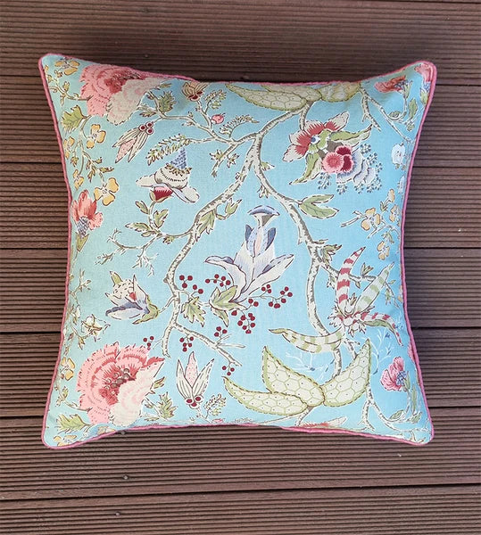Decorative pillow with floral and butterfly pattern on a wooden surface