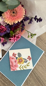 Floral arrangement with a decorative card on a wooden surface