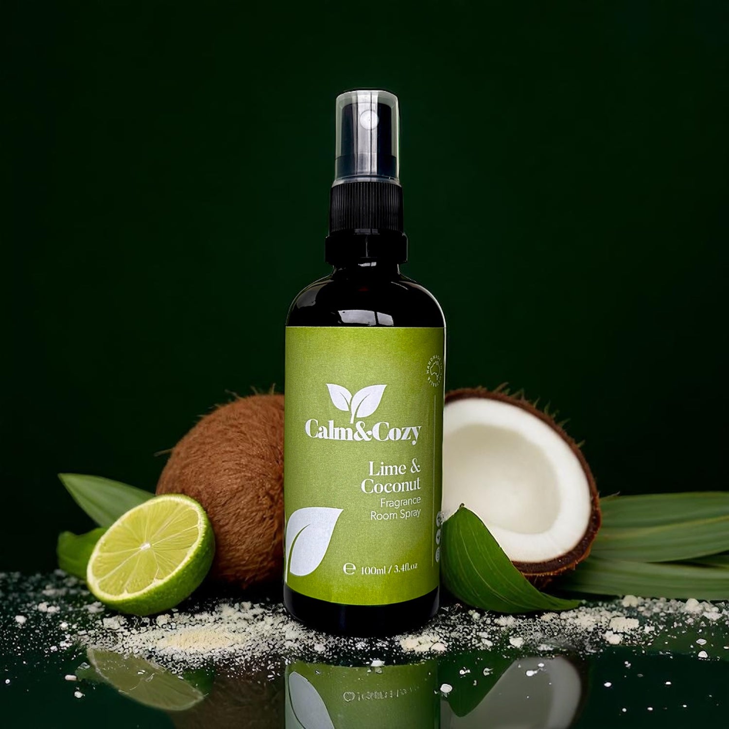 Bottle of Calm & Cozy Lime & Coconut room spray with a lime, coconut, and leaves on a dark background