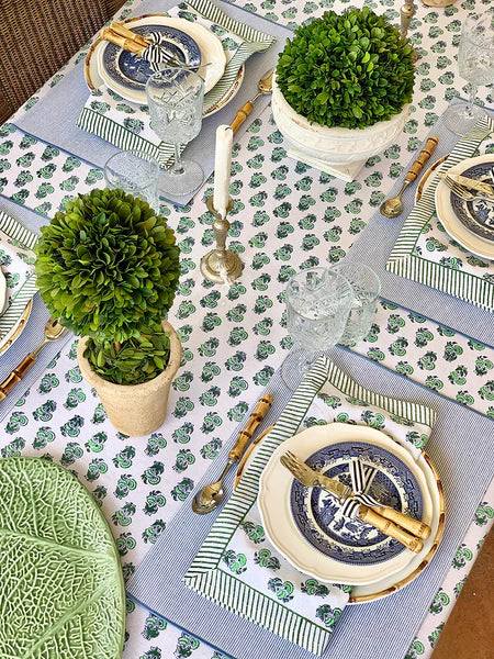 Elegant table setting with green and blue patterns, including plates, cutlery, and decorative elements.