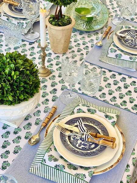 Elegant table setting with blue and white plates, greenery, and patterned tablecloth.
