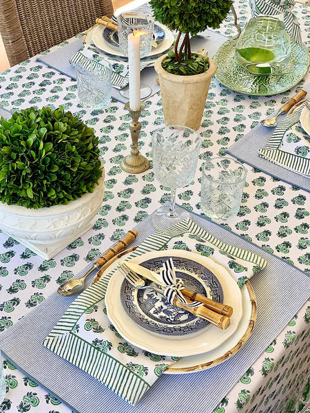 Elegant table setting with green and white decor, including plates, glasses, and place mats.