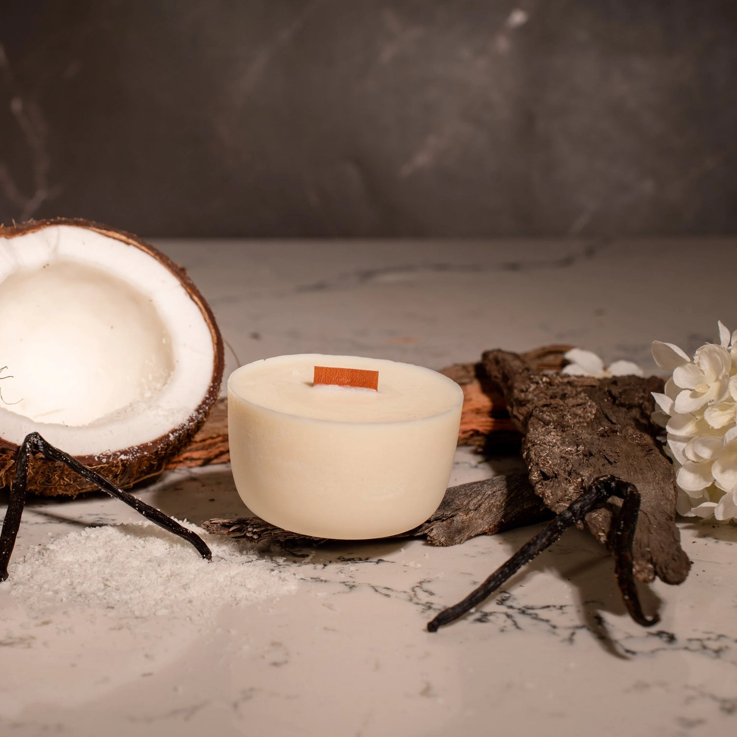 Candle with a coconut and decorative elements on a textured surface