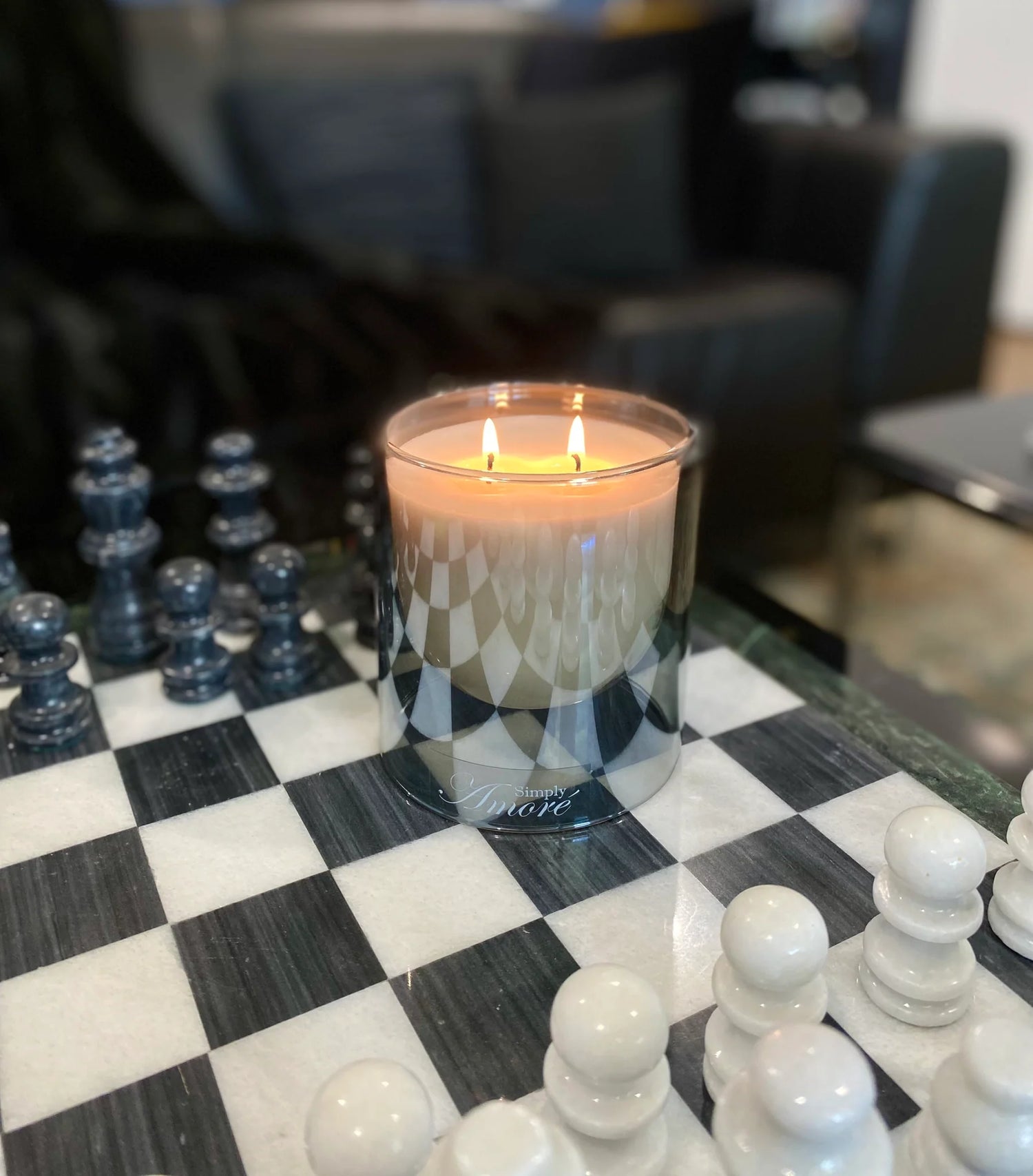 Candle in a glass holder on a chessboard with pieces around