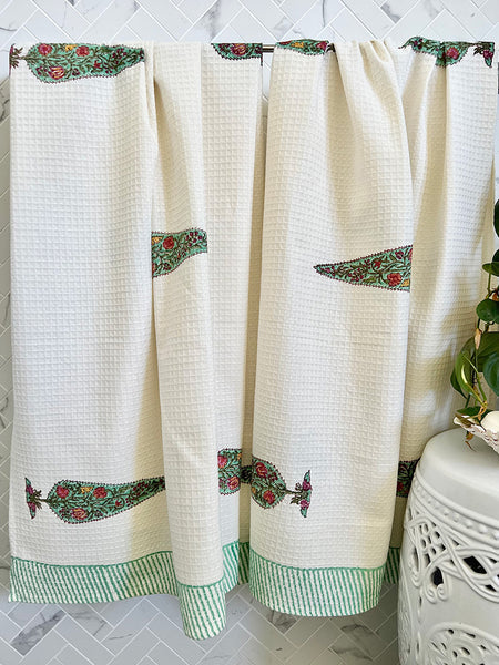 White curtains with green floral embroidery on a tiled wall background